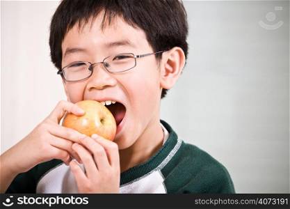 A shot of an asian boy eating an apple