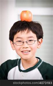 A shot of an asian boy with an apple on top of his head