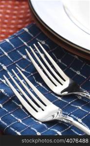A shot of forks and plates on a dining set