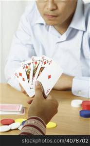 A shot of two young men playing poker with one holding winning cards
