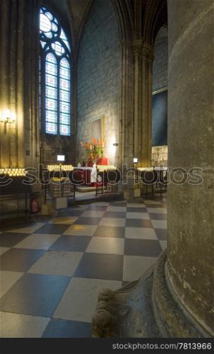 A shrine in the Notre Dame, Paris France with commemorating candles and a small altar. The painting is obscured for coppyright reasons