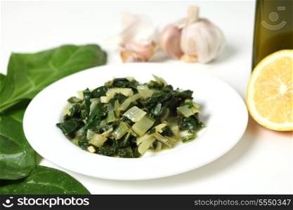 A side dish of swiss chard cooked in olive oil with garlic and chilli flakes and then tossed in lemon juice, with raw ingredients