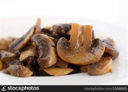 A side view of sauteed mushrooms on a white plate.