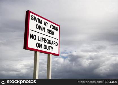 A sign in North Miami Beach indicating that there is no lifeguard on duty in front of ominous, dark clouds.