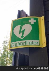 a sign outside indicating a nearby defibrillator yellow and green medical help for heart stroke