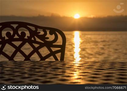 A silhouette of a chair and table at sunrise on the sea beach