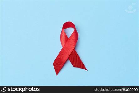 A silk red ribbon in the form of a bow on a blue background, a symbol of the fight against AIDS and a sign of solidarity and support