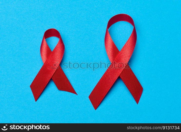 A silk red ribbon in the form of a bow on a blue background, a symbol of the fight against AIDS and a sign of solidarity and support