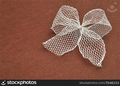 A silver bow isolated on a brown background