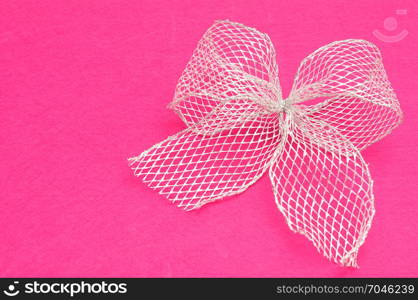 A silver bow isolated on a pink background