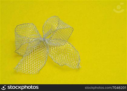 A silver bow isolated on a yellow background