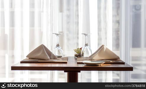 A simple and beautifully arranged table for two, with cloth napkins and wine glasses