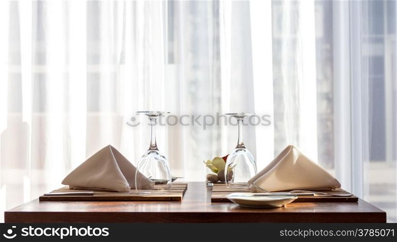 A simple and beautifully arranged table for two, with cloth napkins and wine glasses