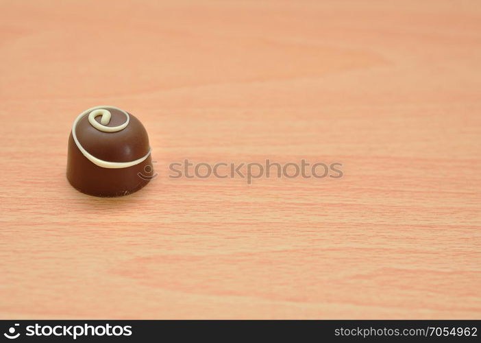 A single chocolate isolated on a wooden background