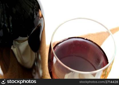 A single glass of red wine viewed from above with the surrounding scenery reflected in the bottle on a light colored background.. Glass Of Red Wine