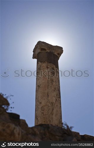 A single pillar put up by Greeks or Romans is backlit by the sun. It stands alone at the ancient city of Ephesus, near Izmir in Turkey.