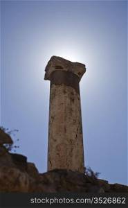 A single pillar put up by Greeks or Romans is backlit by the sun. It stands alone at the ancient city of Ephesus, near Izmir in Turkey.