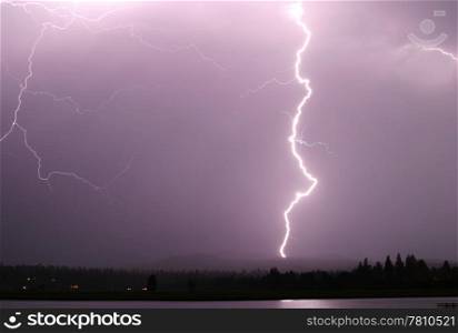 A single strong lightning bolt that reaches from the sky to the ground.