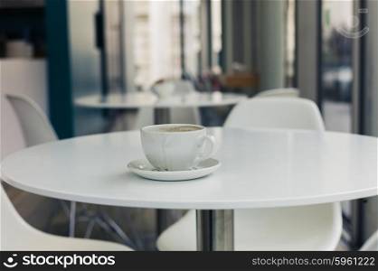 A single tea cup on a white table in a cafe