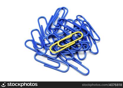 A single yellow paper clip on top of bunch of blue paper clips