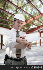 A skeptical looking construction inspector going over his notes and pointing out problems.