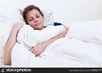A sleeping girl lying in bed holding the blanket.