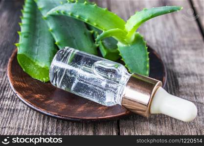 A slice of aloe vera and green leaves with aloe vera essential oil on a wooden table. Skin care products.. A slice of aloe vera and green leaves with aloe vera essential oil on a wooden table.