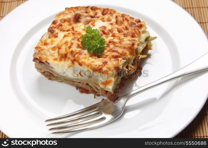 A slice of homemade lasagne verdi on a plate with a fork, high angle view