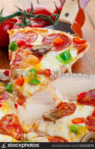 A slice of hot pizza deluxe with pepperoni, mushrooms, peppers, and lots of gooey mozzarella cheese, ready to be served.