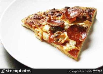 A slice of thin crust pepperoni and beef pizza on a plate