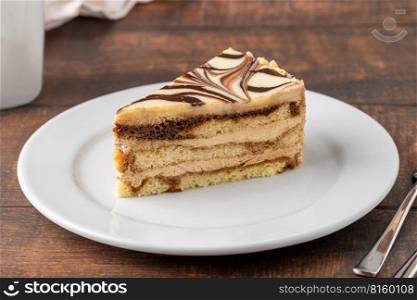 A slice of white chocolate and caramel cake on wooden table