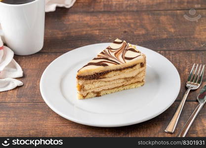 A slice of white chocolate and caramel cake on wooden table