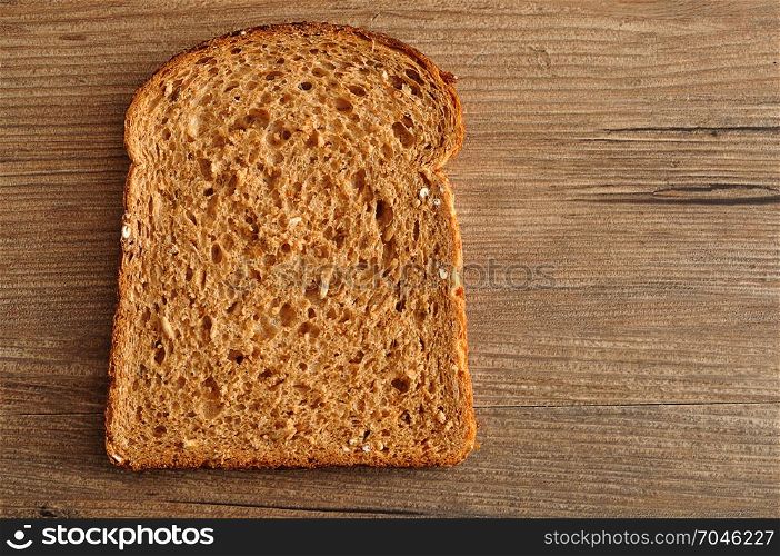 A slice of whole wheat bread displayed on a wooden table