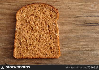 A slice of whole wheat bread displayed on a wooden table