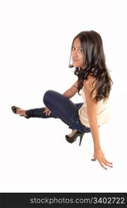 A slim and pretty Asian woman crouching on the floor in jeans and withlong brunette hair and in profile, for white background.