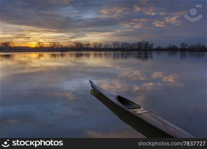 a slim sea kayak ready for paddling workout before sunrise on a calm lake in Colorado
