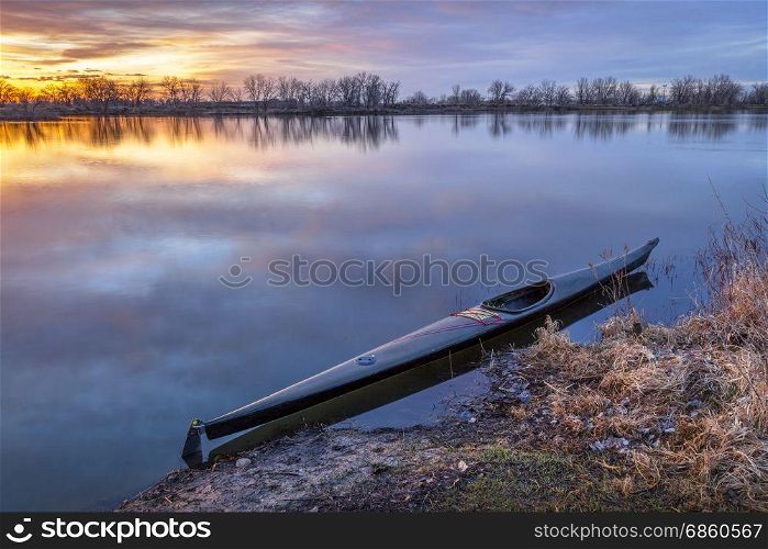 a slim sea racing kayak ready for paddling workout before sunrise on a calm lake in Colorado
