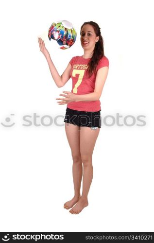 A slim young woman standing bar feet in the studio and playing with acolorful soccer ball, in short black shorts, for white background.