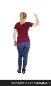 A slim young woman standing in jeans and a burgundy sweater fromthe back, pointing with one finger up, isolated for white background