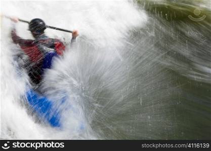 A slow shutterspeed shot of a kayaker in very rough whitewater. Shot with copyspace on the right hand side of the frame.