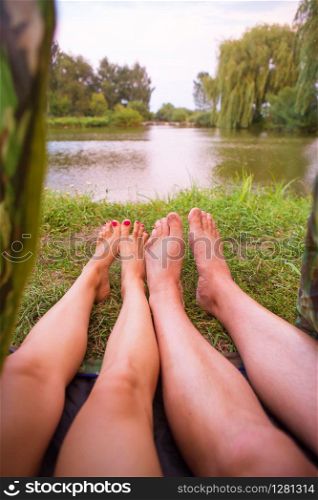 A small camping tent on the lake, a night&rsquo;s lodging and the feet of a young couple.. A small camping tent on the lake, a night&rsquo;s lodging and the feet of a young couple