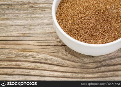 a small ceramic bowl of gluten free teff grain against weathered wood background