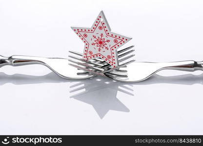 A small Christmas tree decoration on two forks on a white background. Christmas table set concept. A small Christmas tree decoration on two forks on a white background