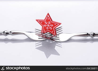 A small Christmas tree decoration on two forks on a white background. Christmas table set concept. A small Christmas tree decoration on two forks on a white background