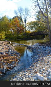 A small creek running from a small lake into the lake Ontario in the fallunder bright sunshine.