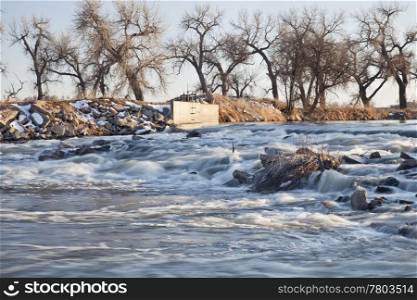 a small dam diverting water to farmland irrigation, South Platte River in eastern Colorado near Greeley, winter scenery