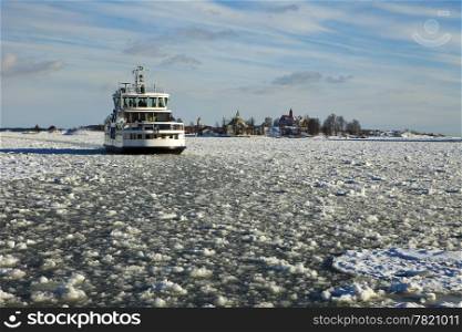 A small ferry boat takes passengers from Luoto Island to Helsinki in the middle of the winter. The harbor is filled with small ice chunks.