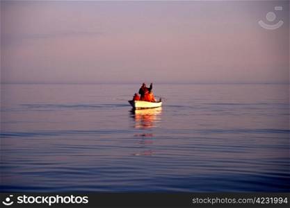 A small fishing boat with fishermen in sunset/sunrise