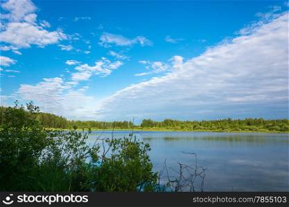 A small lake in the forested shores and a beautiful cloudy sky, Russia.