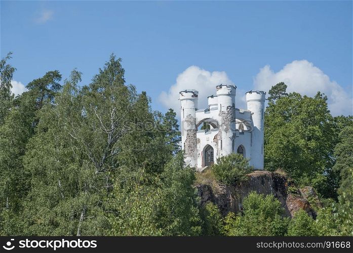A small mountain with a white tower on top.. White tower on a rock